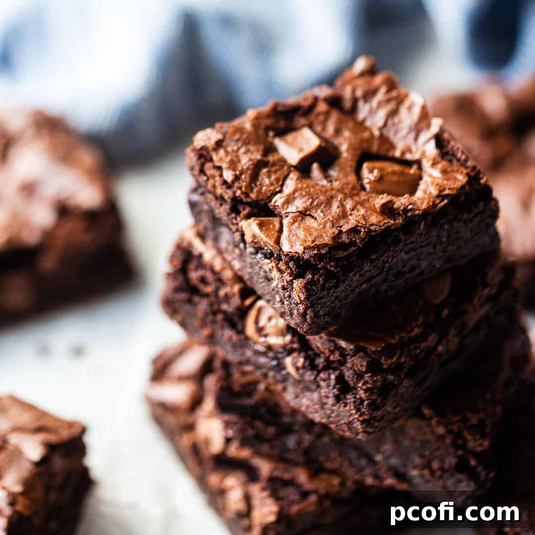 A stack of perfectly baked brownie bars, showcasing their rich, fudgy texture, with a soft blue kitchen towel in the background.