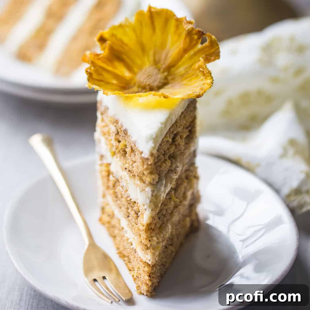 A tempting slice of hummingbird cake, complete with rich cream cheese frosting and a delicate dried pineapple flower garnish, served on a white plate.