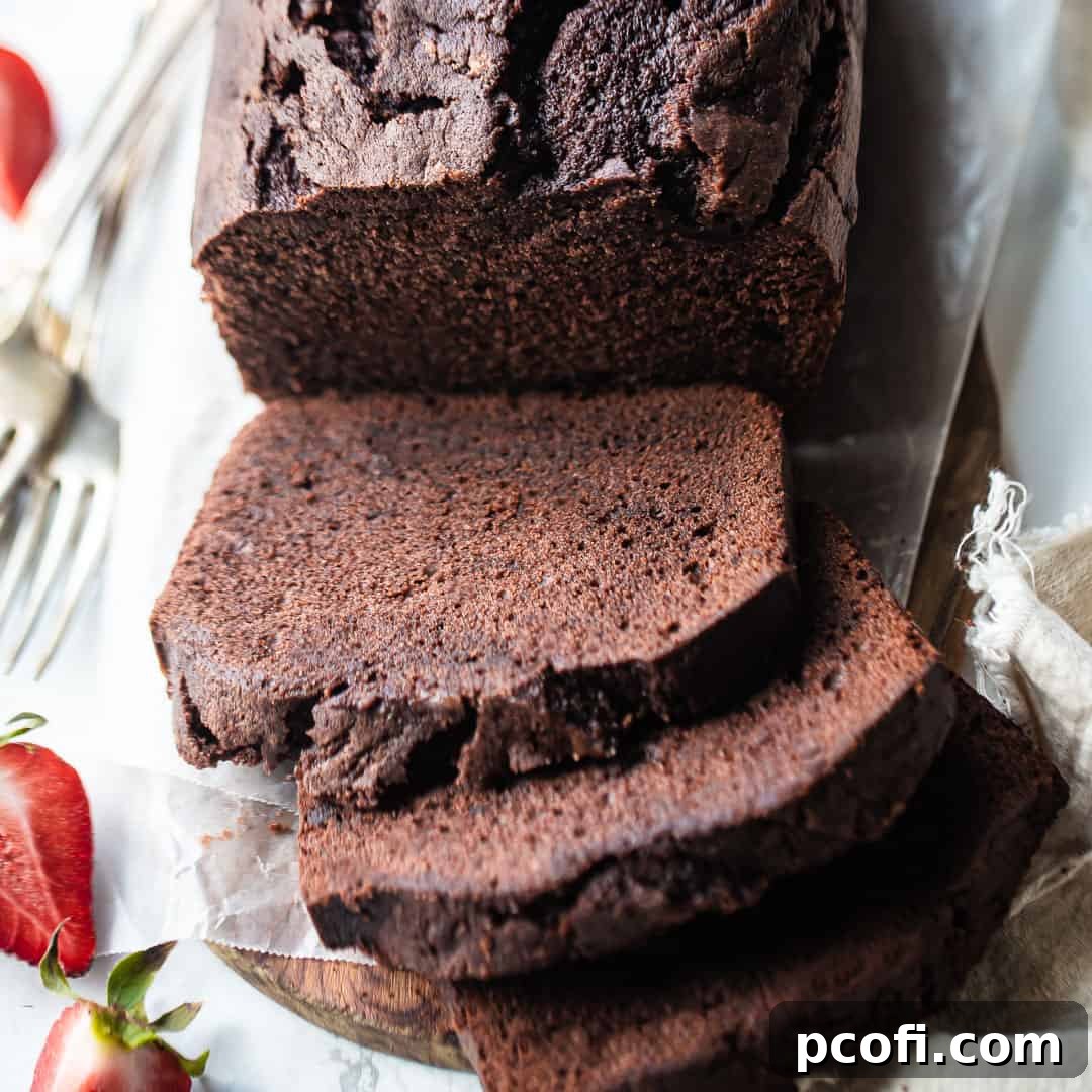 Rich chocolate pound cake, elegantly sliced and served on a rustic wooden board, showcasing its dense and moist texture.