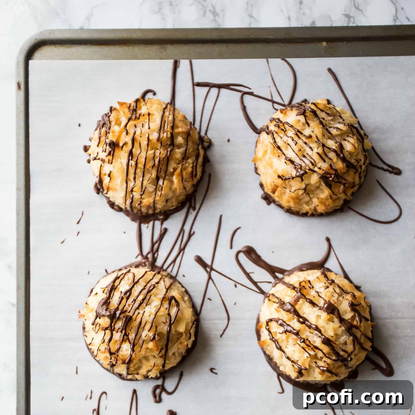 An overhead close-up shot of perfectly golden coconut macaroons, artfully drizzled with rich dark chocolate, showcasing their enticing texture.