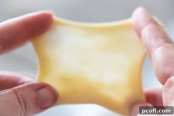 A baker performing the windowpane test on yeast dough, stretching it thin enough to be translucent.