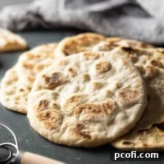 Pita breads in a pile on a dark green background.