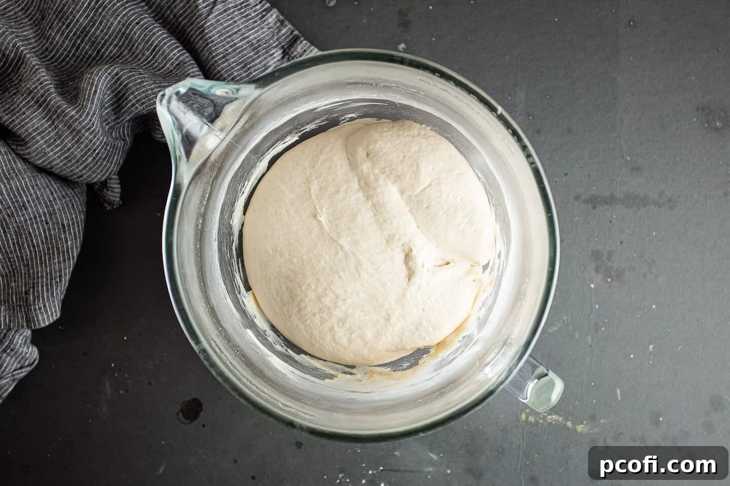 Pita bread dough significantly risen, showing it has doubled in volume after an hour of proofing.