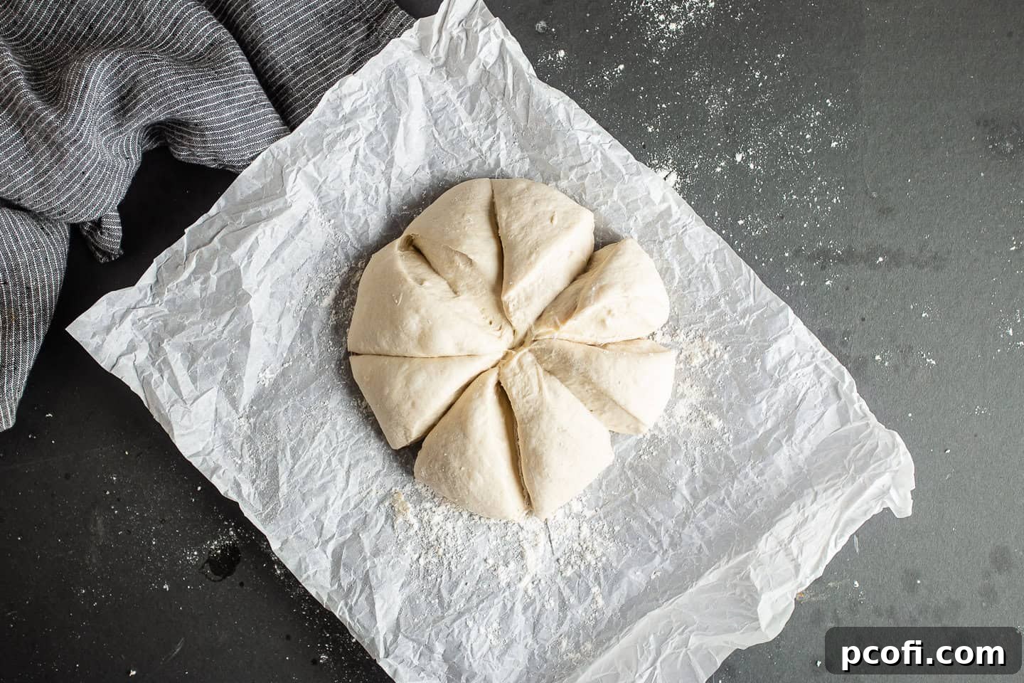 Pita bread dough being divided into eight equal portions using a pastry scraper on a floured surface.