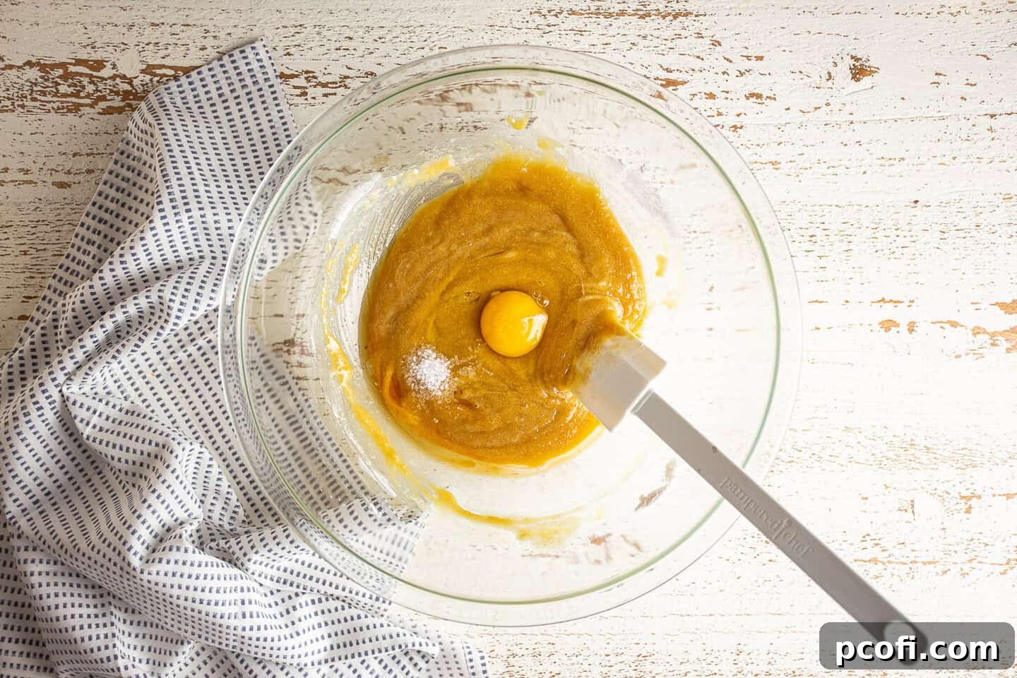 Adding eggs, vanilla, and salt to melted butter, sugar, and flour mixture.