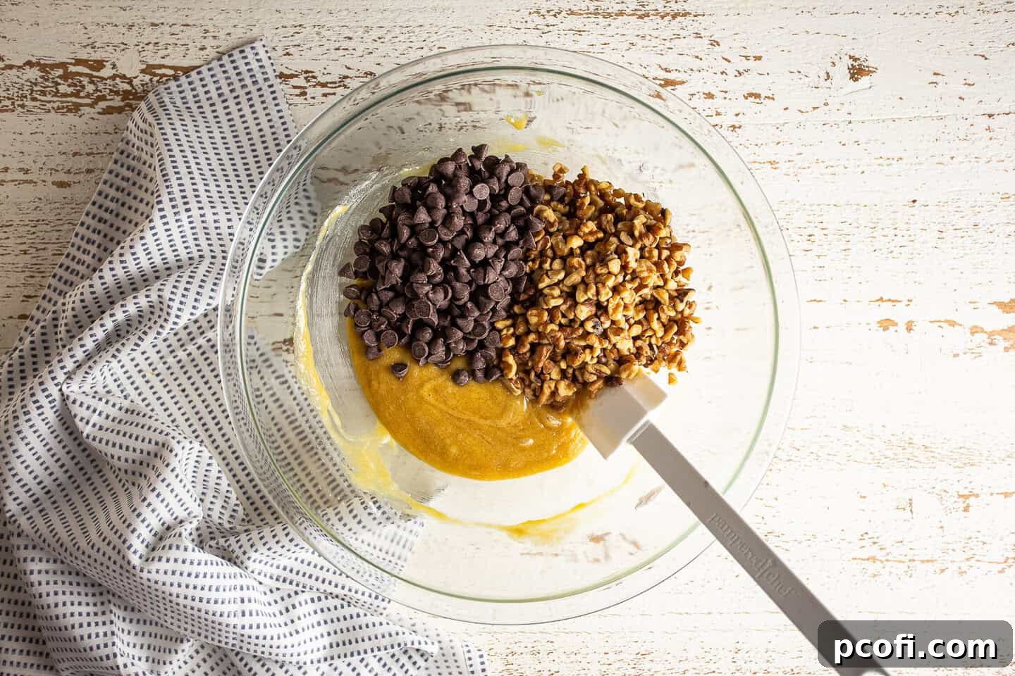 Adding nuts and chocolate chips to derby pie filling.