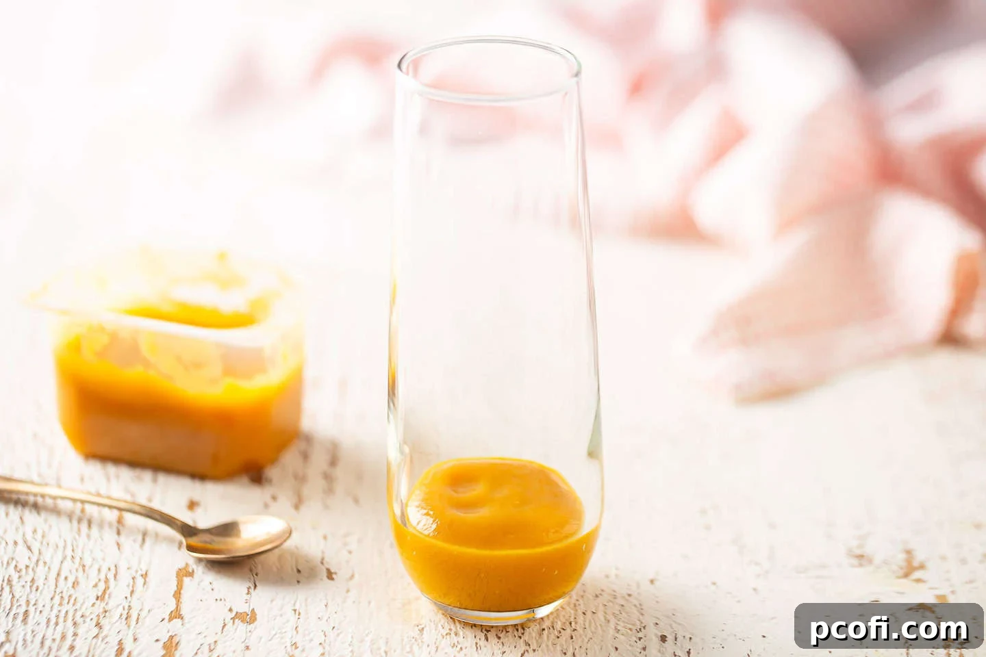 A close-up shot of peach puree meticulously placed at the bottom of a clear champagne flute, ready for the sparkling wine.