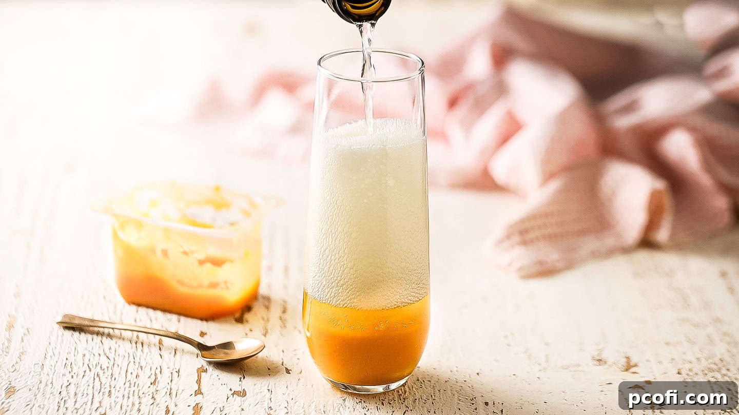 Sparkling Prosecco being slowly poured into a champagne flute, mixing with the peach puree at the bottom, creating a beautiful bubbly cascade.