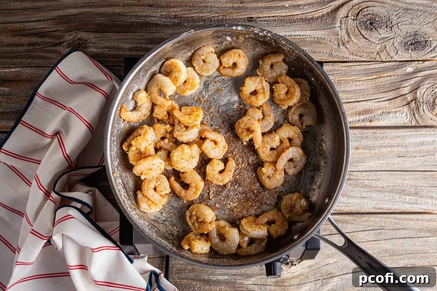 Sprinkling flour over searing shrimp to create a roux.