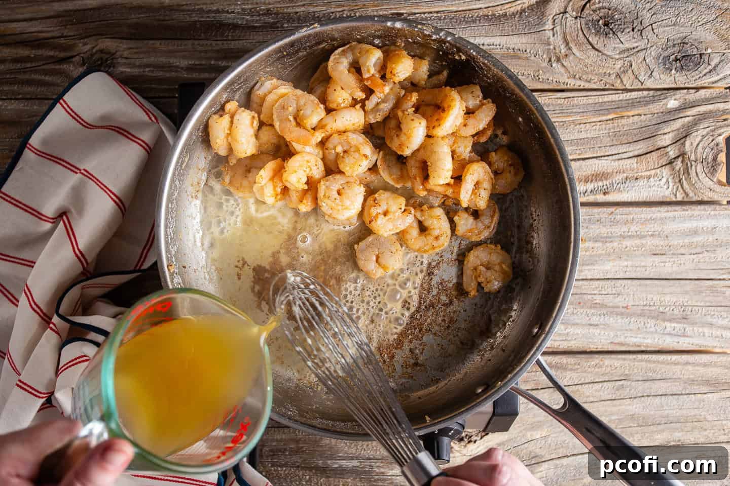 Adding chicken stock to shrimp and roux to make a sauce.