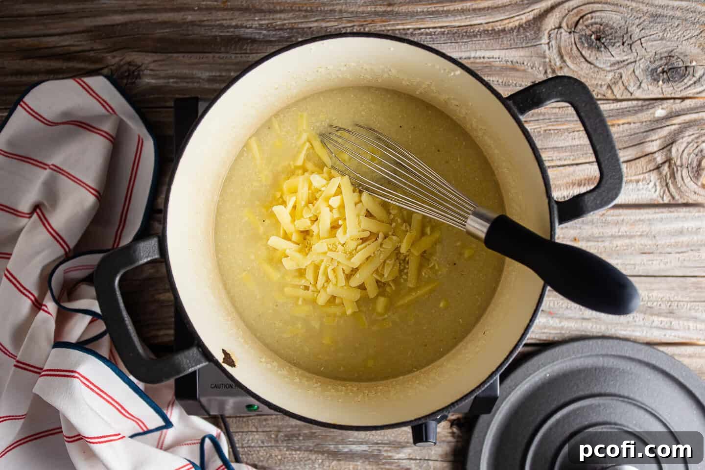 Adding shredded cheese to grits.