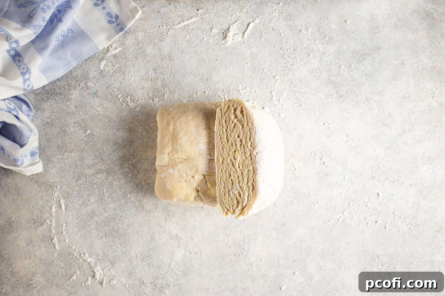 Laminated croissant dough being divided evenly in half with a knife.