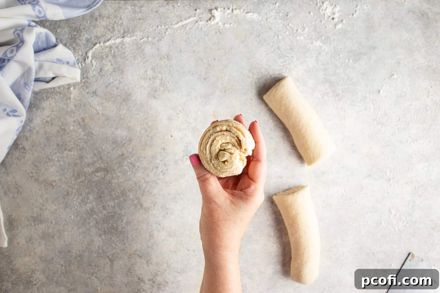 Cruffin dough being twisted and spiraled into individual bun shapes, ready for baking.