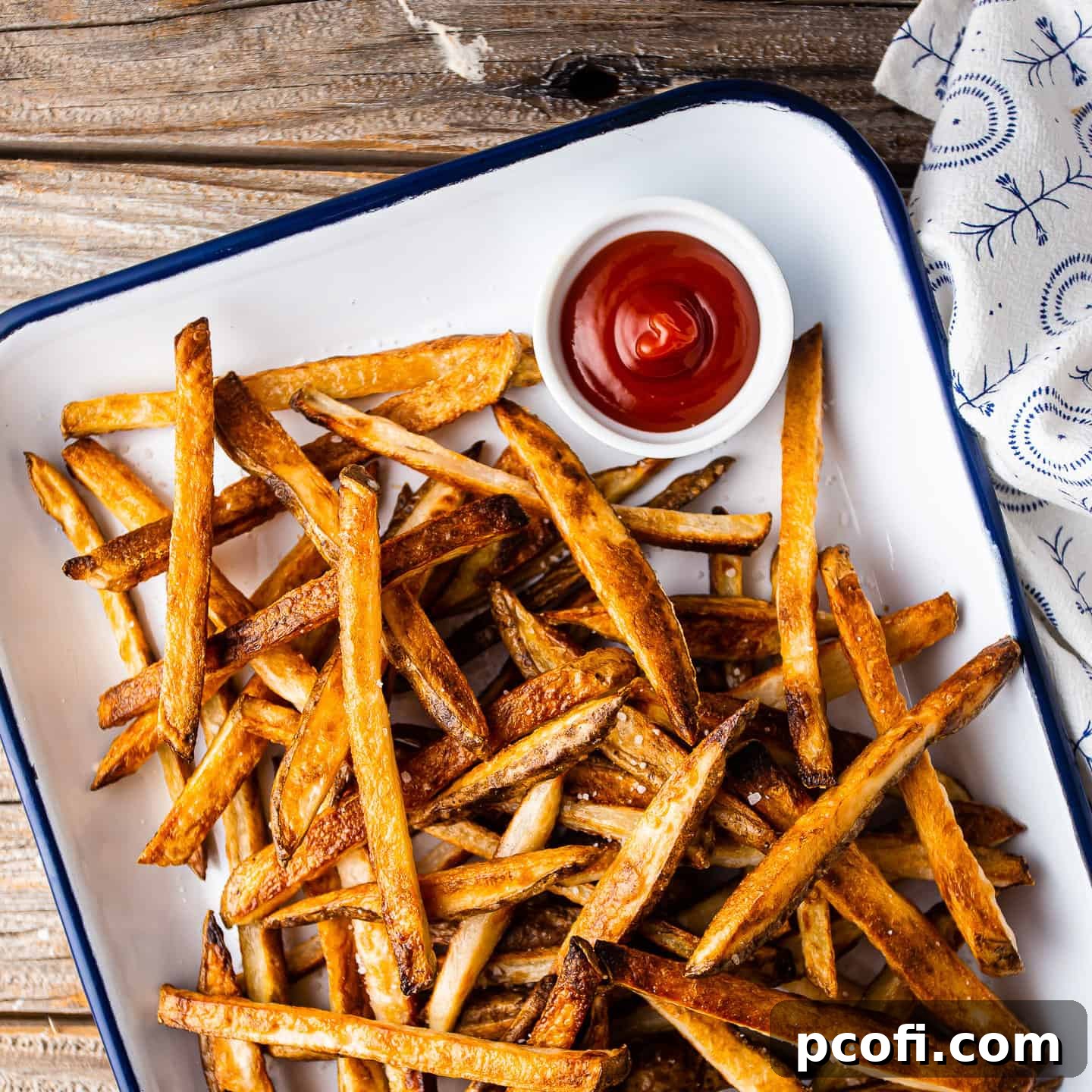 Baked oven fries sprinkled with salt and served on a tray with ketchup.