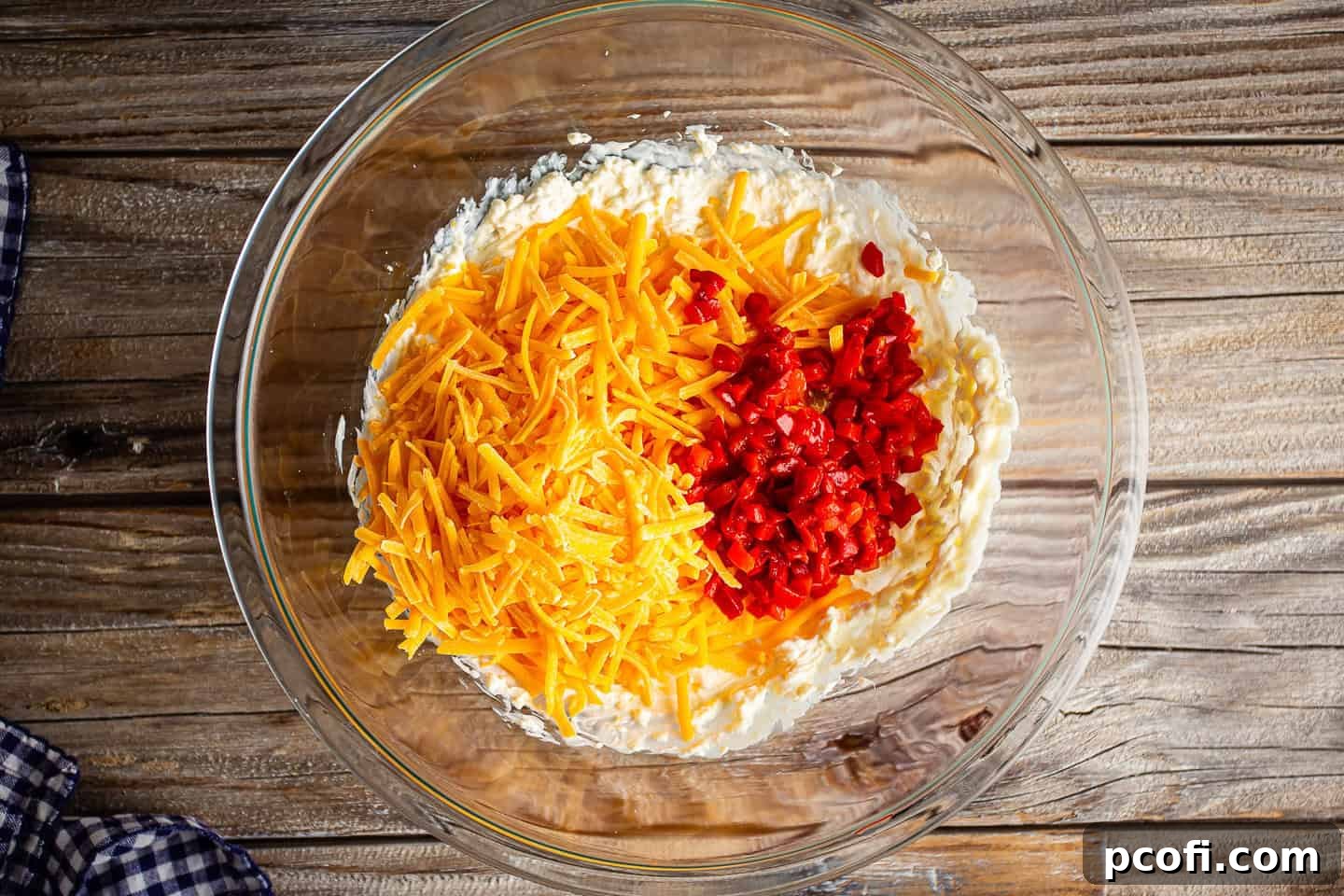 Adding shredded cheddar cheese and diced pimentos to base.