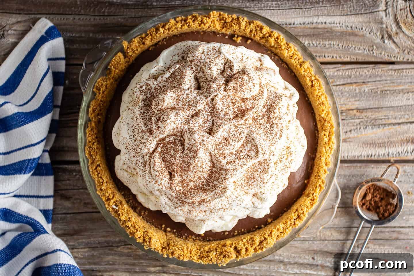 A finished homemade chocolate pudding pie, garnished with a light dusting of cocoa powder, ready to be served.