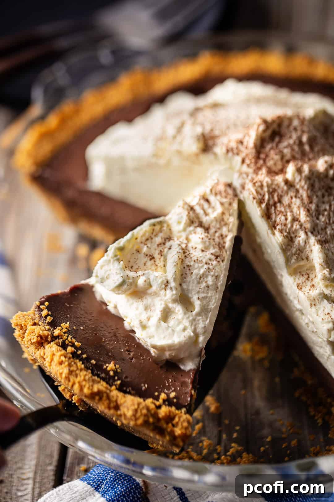 A slice of homemade chocolate pudding pie with generous whipped cream, served on a dark blue plate, ready to be enjoyed.