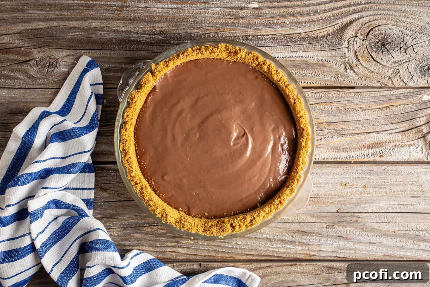 Warm, freshly made homemade chocolate pudding is poured into a graham cracker crust, ready to be chilled and set.