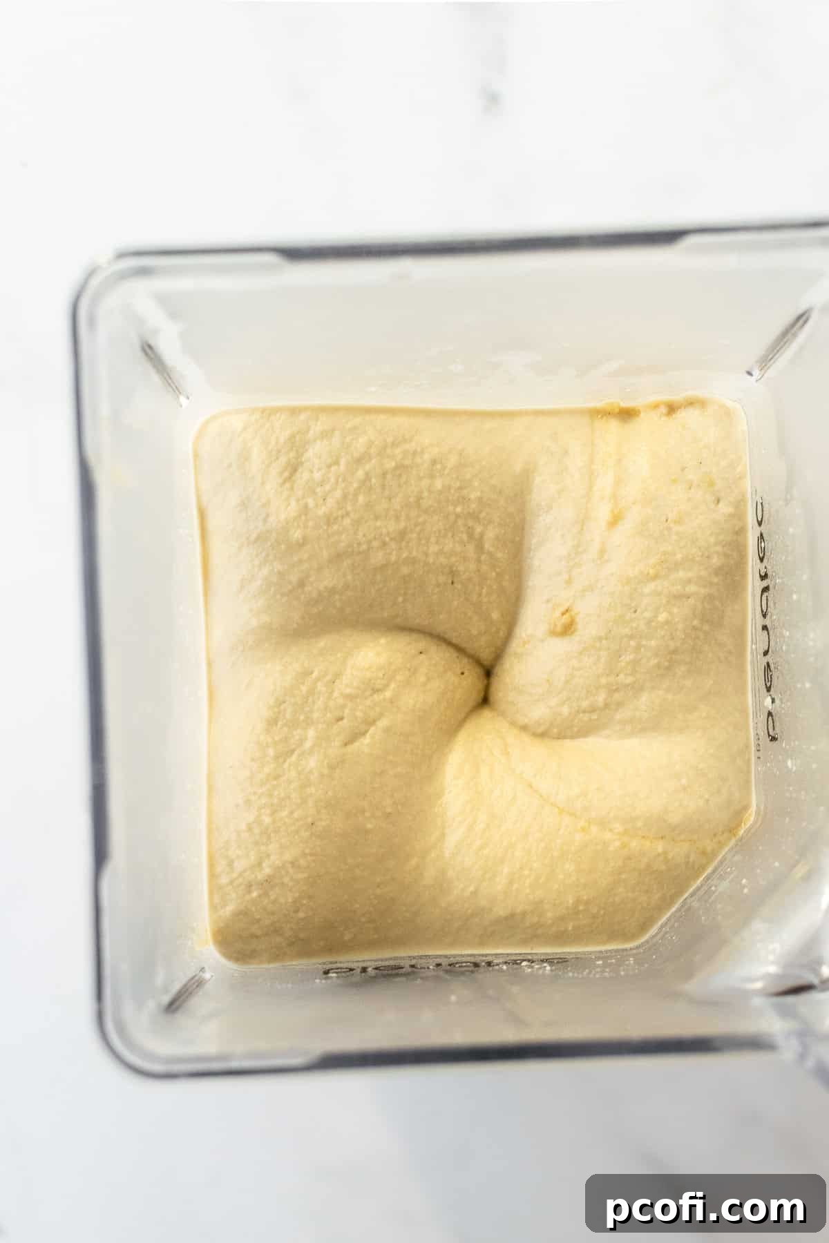 Creamy, blended hummus in a food processor, mid-preparation.