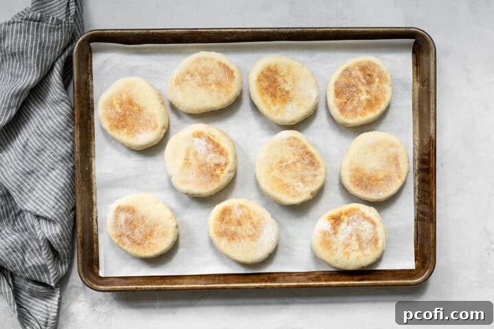 English muffins browning in a non-stick skillet on the stovetop.