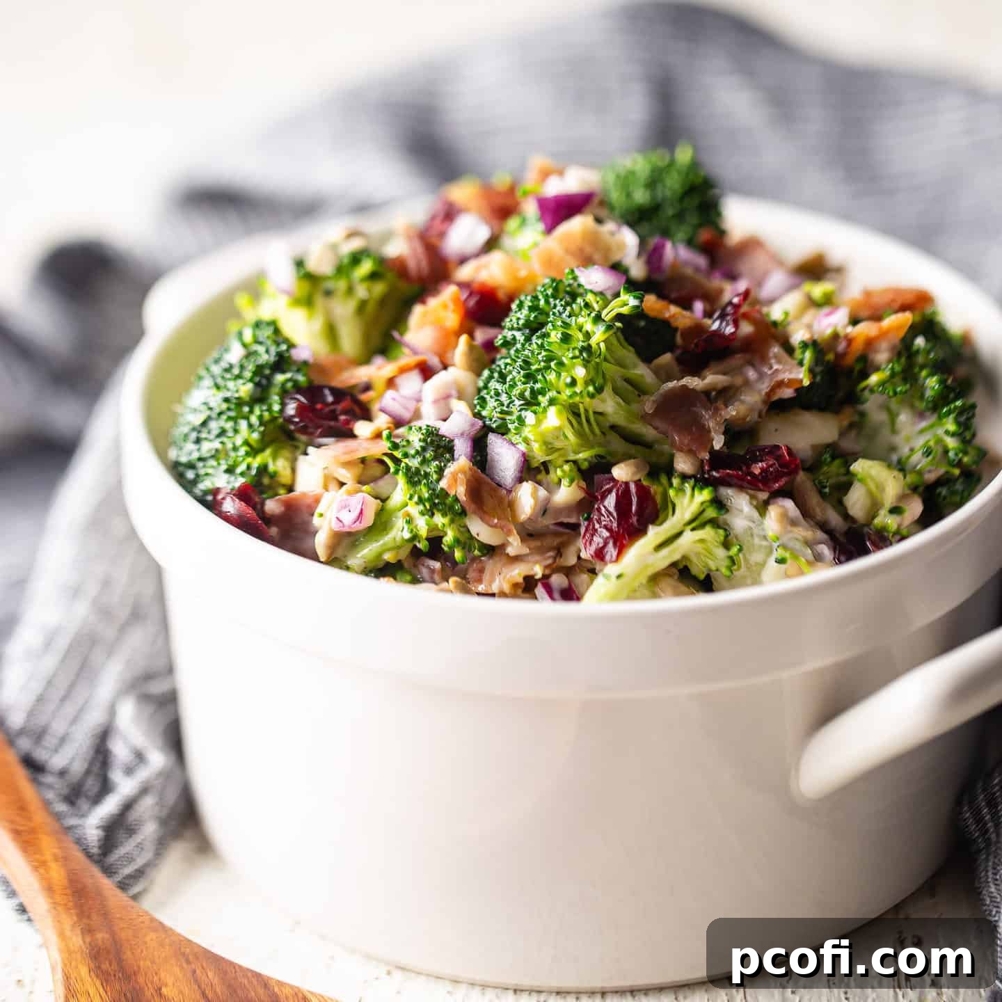 Freshly made broccoli salad in an elegant white serving bowl with handles, ready to be enjoyed.