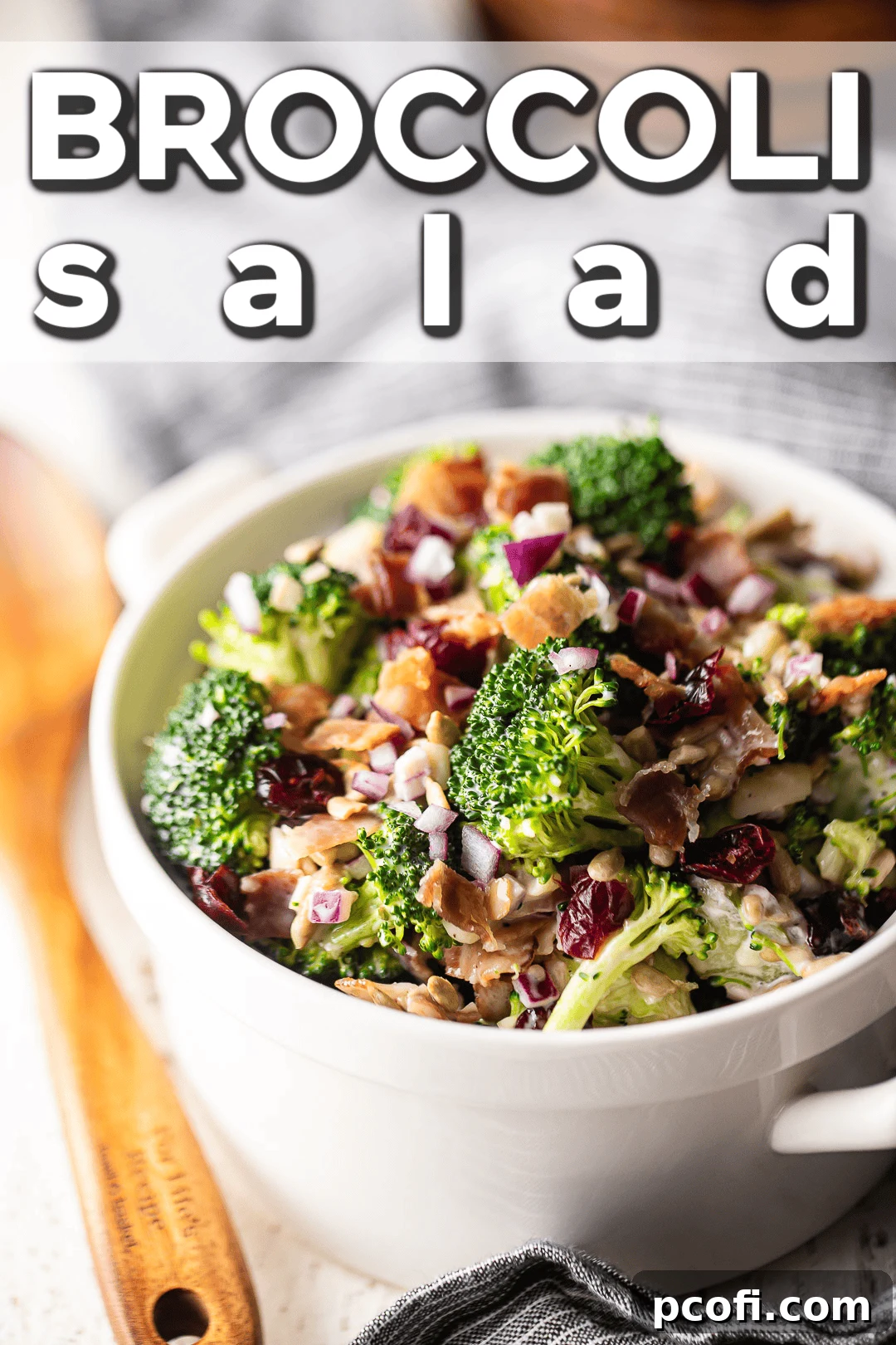 A close-up view of the delicious broccoli salad, beautifully arranged on a white serving surface with rustic wooden utensils in the background, highlighting its rich texture and vibrant colors.