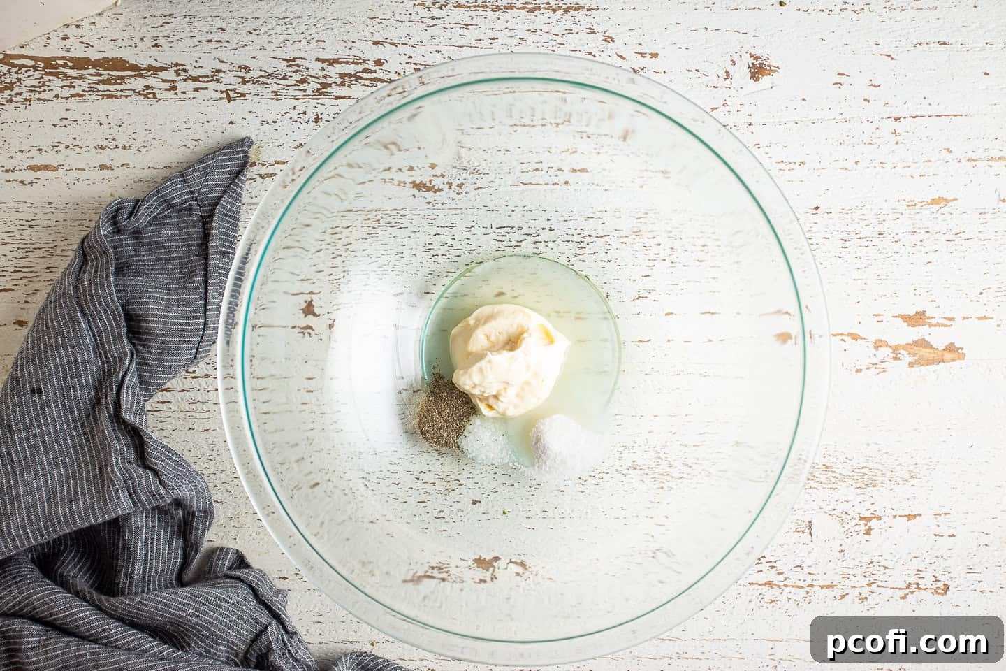Ingredients for the creamy broccoli salad dressing are mixed together in a large glass bowl, showing the initial stage of preparation.