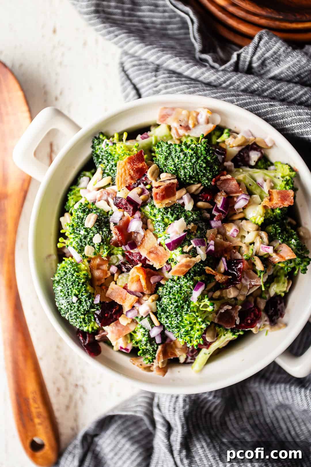 A close-up of the delightful broccoli salad recipe, exquisitely prepared and presented, featuring a stylish black and white striped cloth in the background, enhancing its visual appeal.