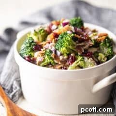 Broccoli salad in a white serving bowl with handles.