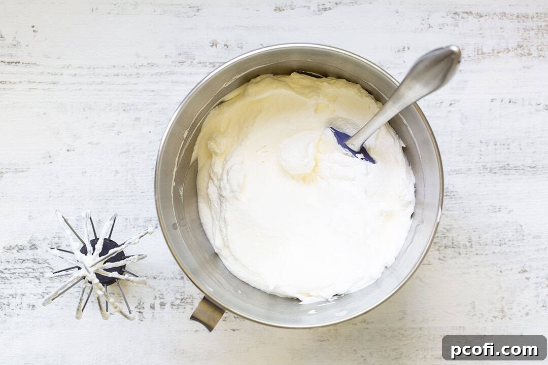 Whipped cream in a stand mixer bowl, showing stiff peaks