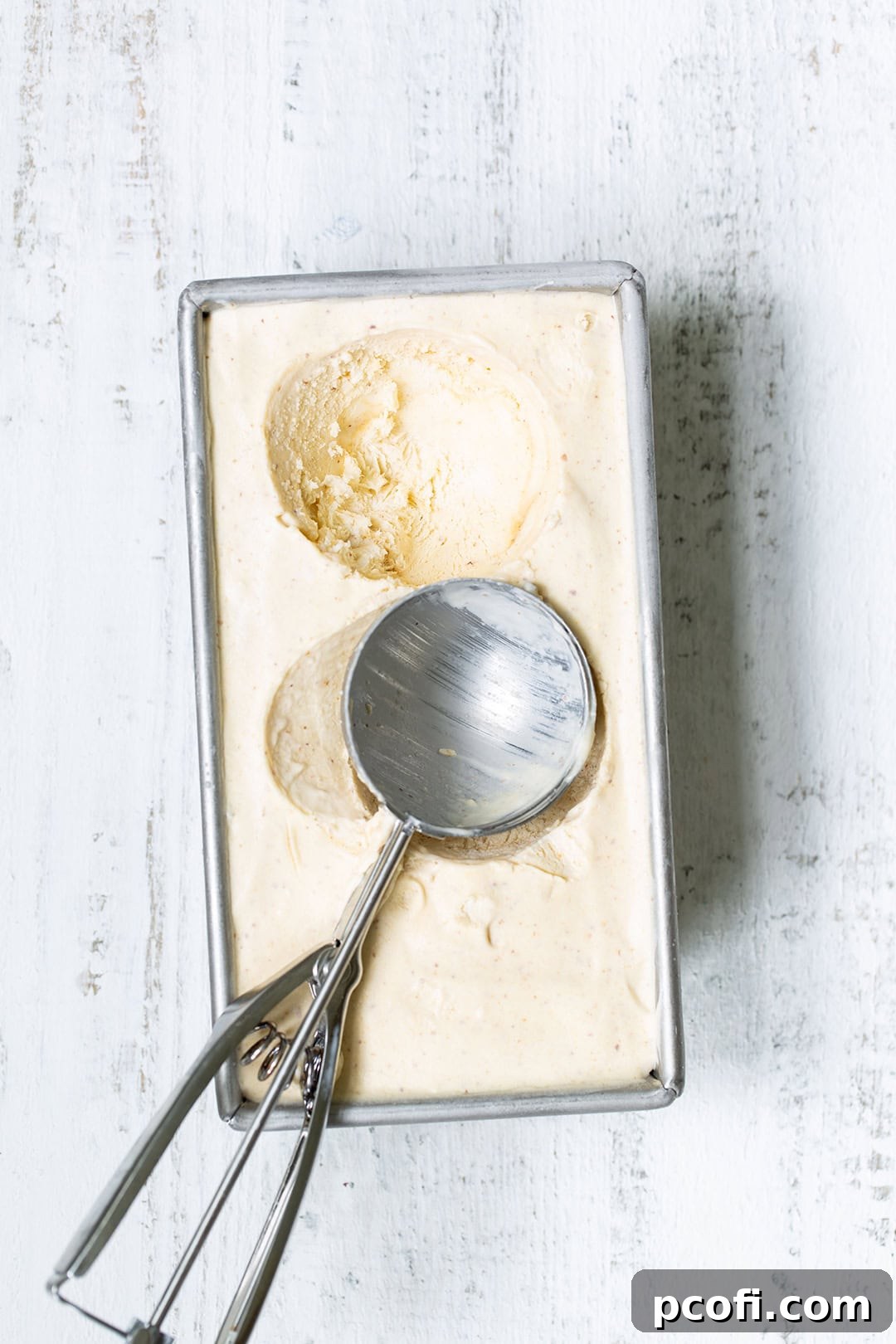 Scoop of peach ice cream in a bowl with an ice cream scoop