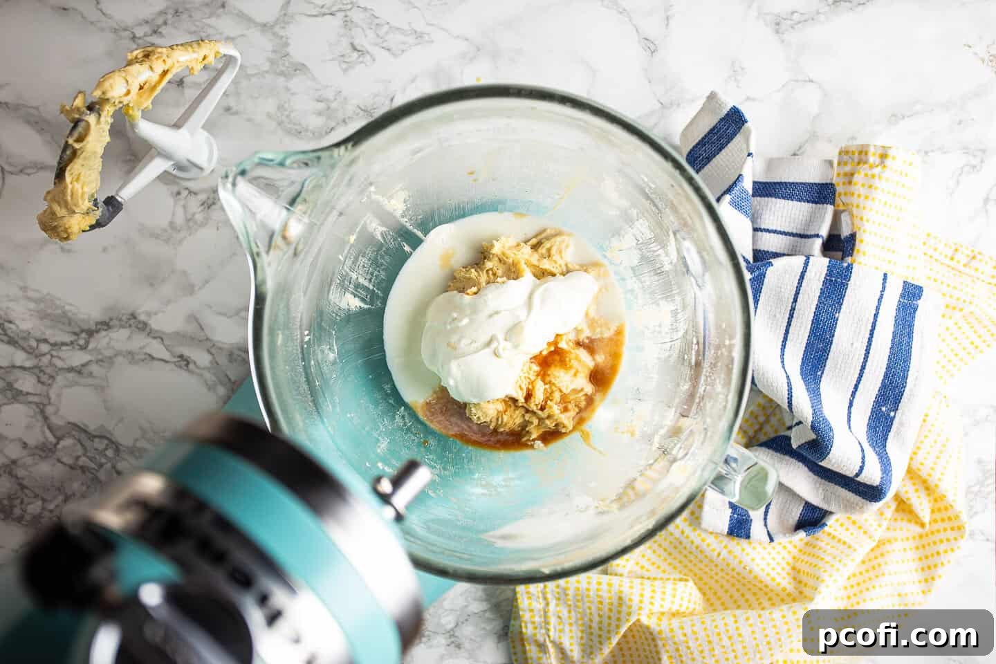 Pouring sour cream, milk, and vanilla extract into the cake batter, preparing for final mixing.