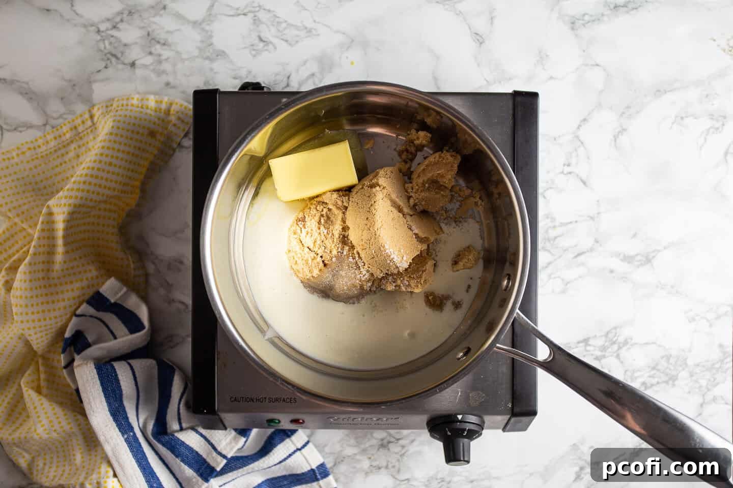 A medium pot on the stove, containing brown sugar, butter, heavy cream, and salt, beginning to melt for the butterscotch icing.