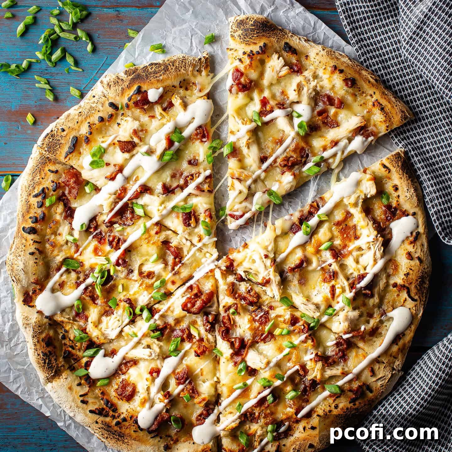 Chicken bacon ranch pizza cut into slices and presented on a blue background.