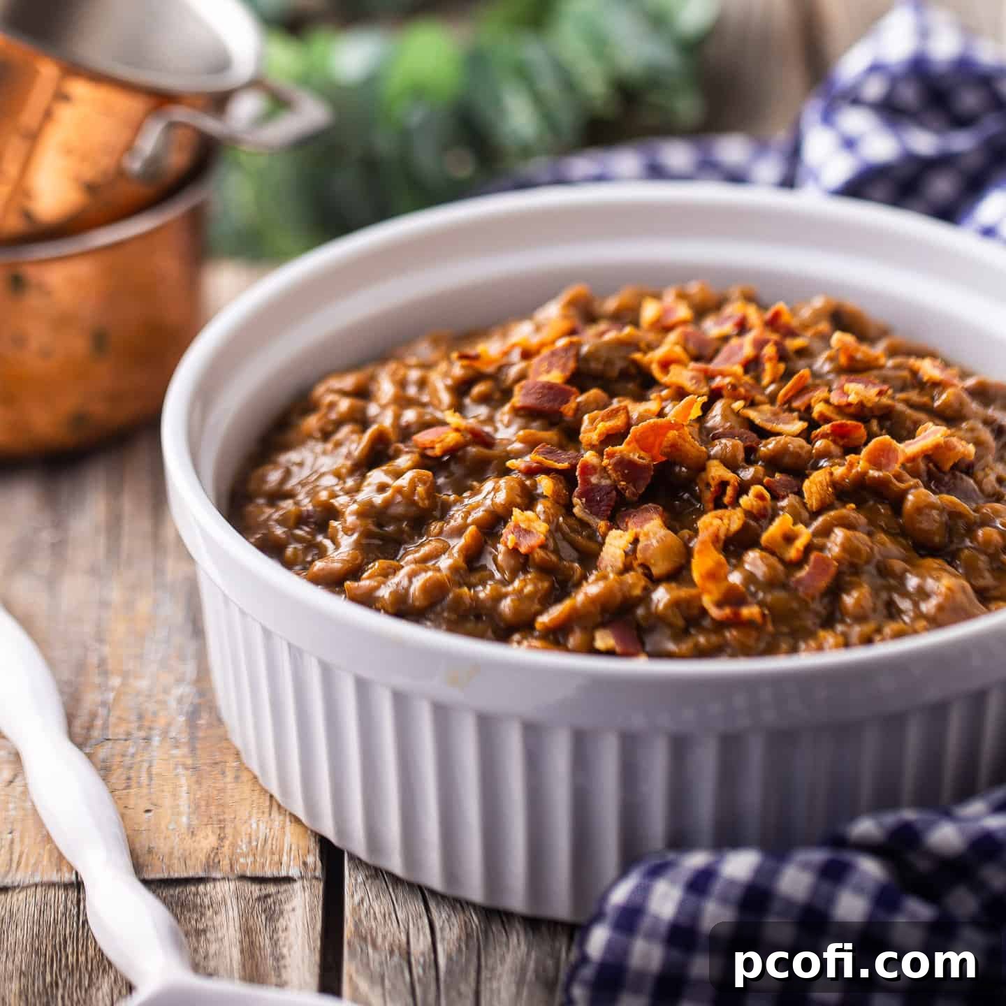 Baked beans served in a casserole dish and topped with bacon.