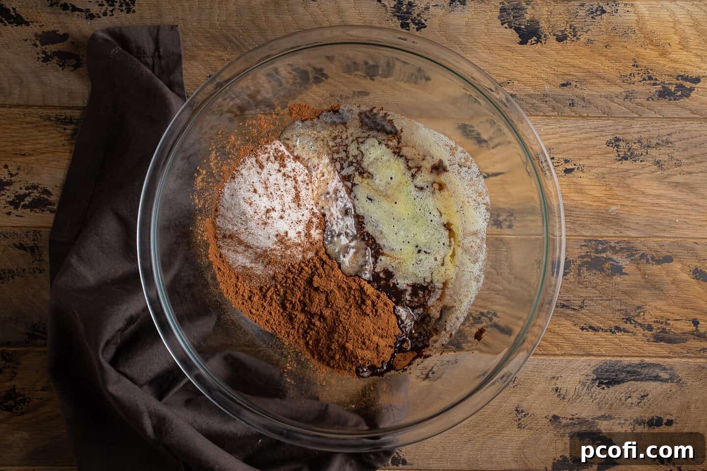 Sugar, cocoa, and melted butter in a large glass mixing bowl.