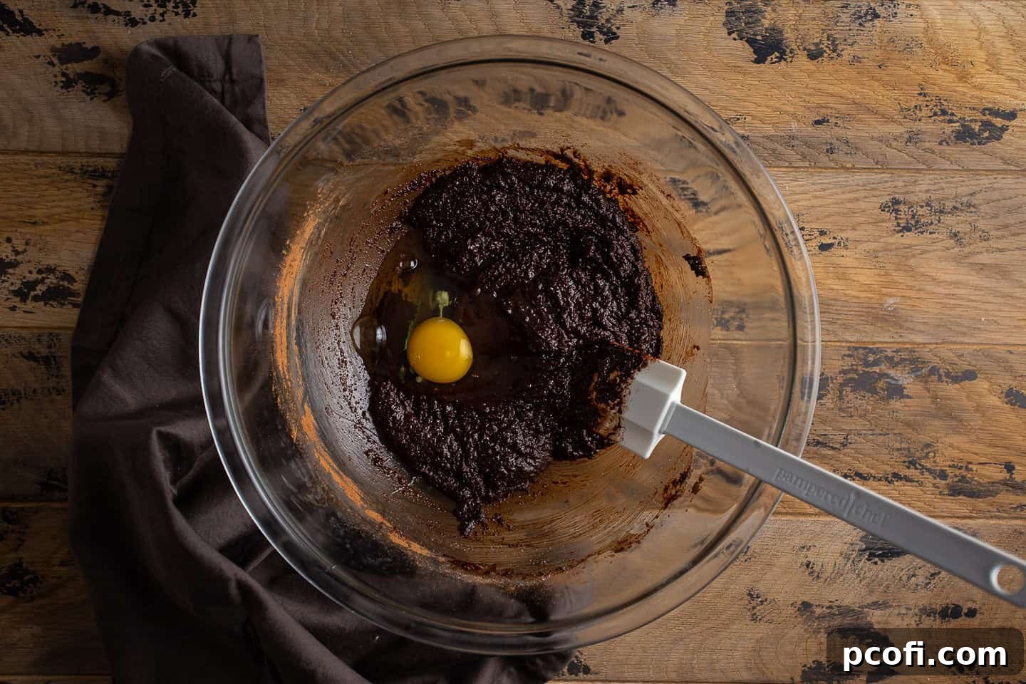 Adding the first egg to brownie batter.