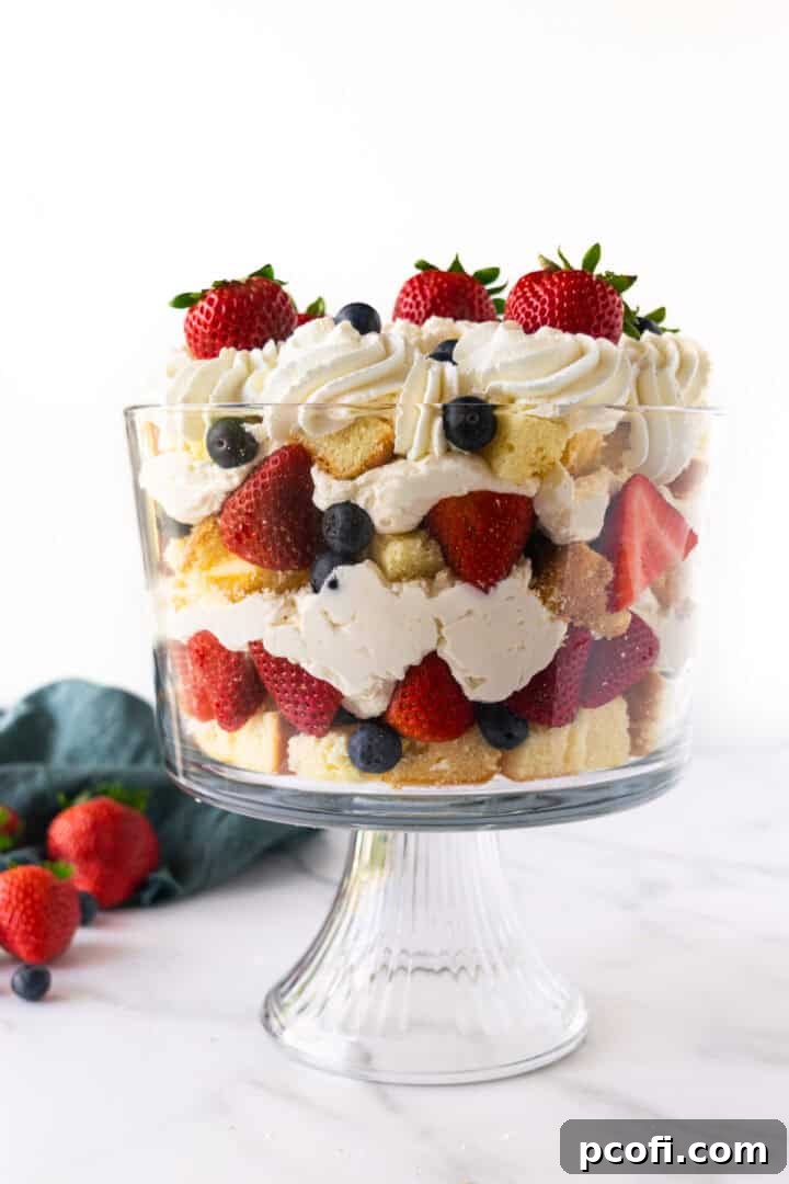 A tempting no-bake cheesecake berry trifle, beautifully presented in a clear bowl with visible layers of pound cake, creamy filling, and fresh berries.