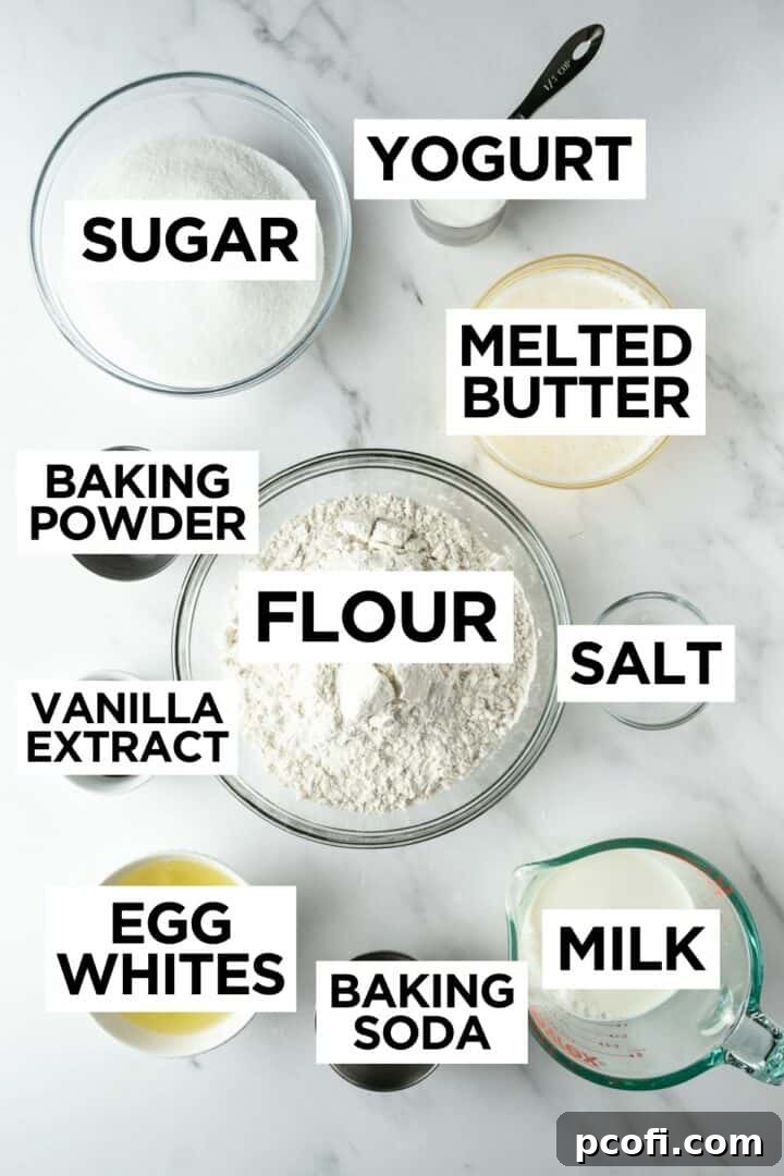 A collection of ingredients for an American flag cake, including flour, sugar, butter, and milk, laid out in bowls on a clean white table.
