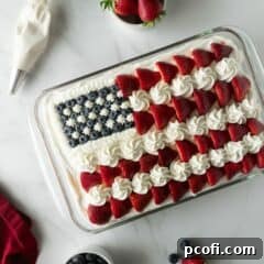 An American flag cake in a baking pan, beautifully frosted and decorated with strawberries and blueberries, ready to be served.