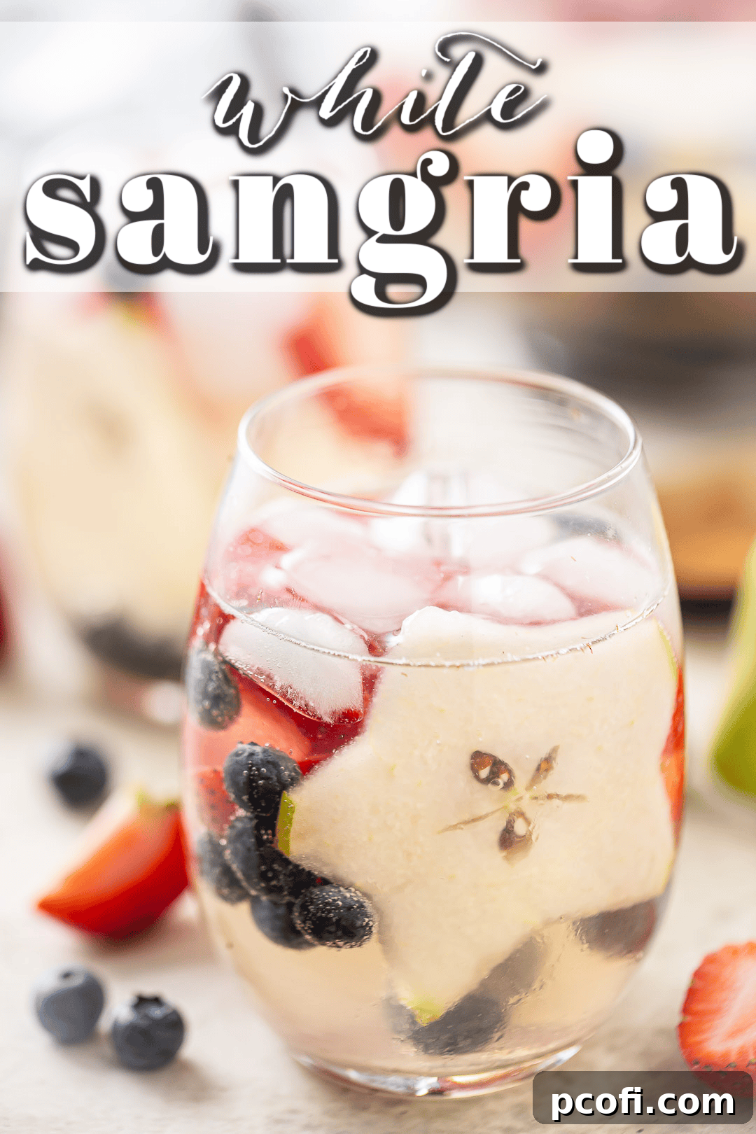 White sangria in a glass with strawberries, blueberries, and pear.