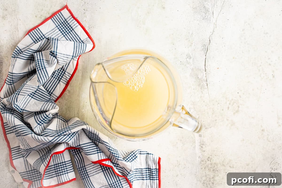 Adding liquid ingredients to a glass pitcher to make white sangria.