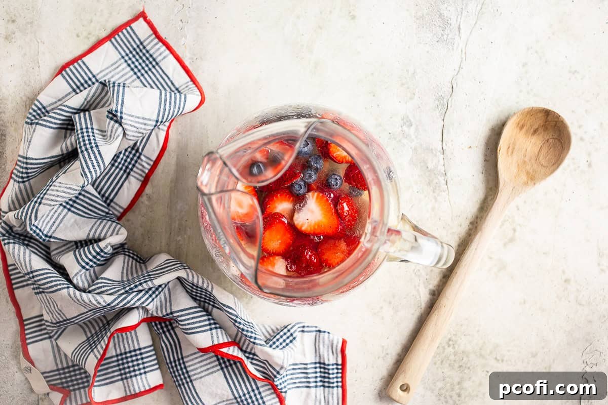 Adding berries to a pitcher of white sangria.