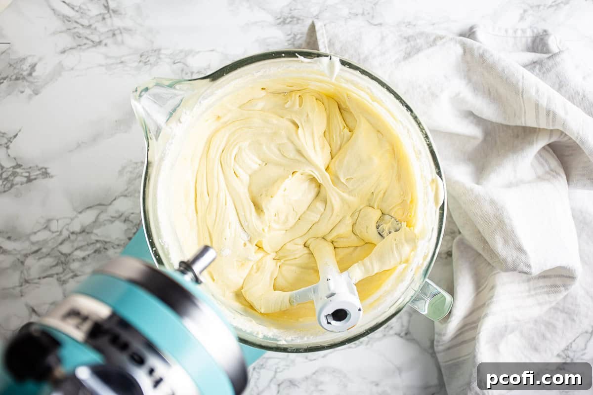 Cream cheese pound cake batter in a large glass mixing bowl.