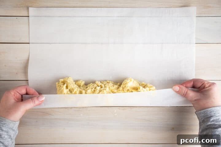 Rolling butter cookie dough into uniform logs, a perfect preparation step for slice-and-bake cookies.