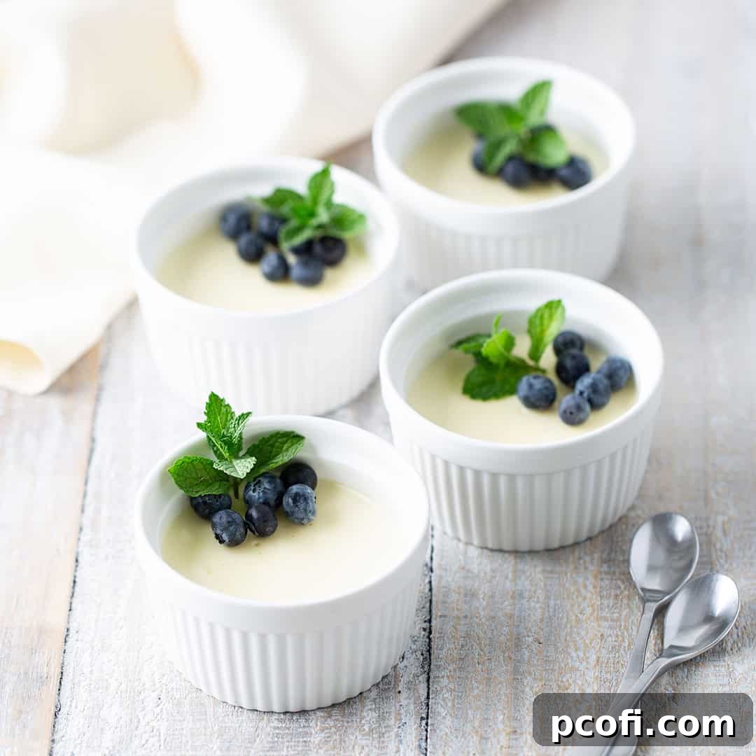 Four individual servings of creamy lemon posset, beautifully presented in ramekins with a garnish of fresh berries.