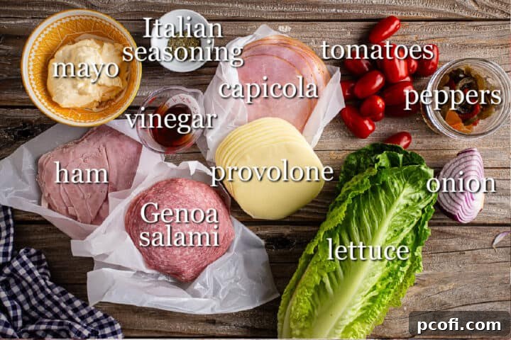 All the fresh ingredients laid out for making Italian Hoagie Dip, including various deli meats, cheese, mayonnaise, vinegar, and chopped vegetables.