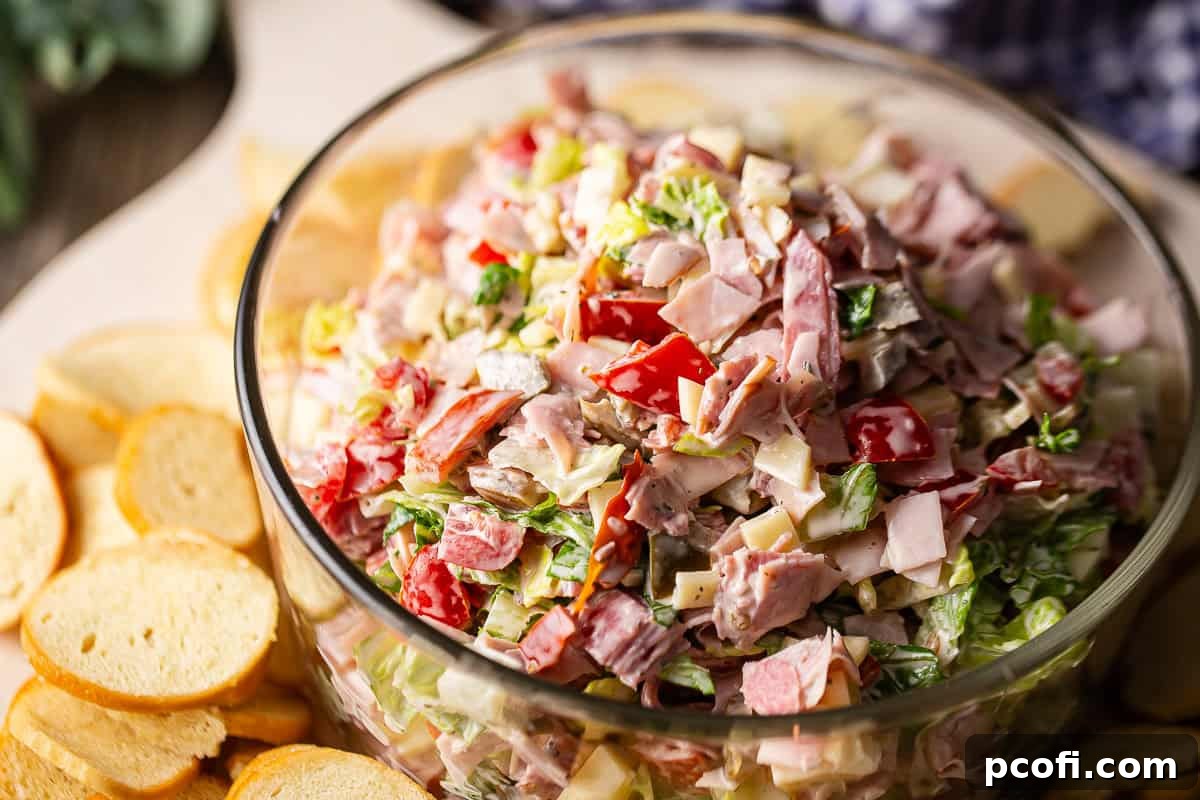 A vibrant close-up shot of a bowl of Italian hoagie dip, showing the intricate textures and colors of the mixed deli meats, cheese, and fresh vegetables.