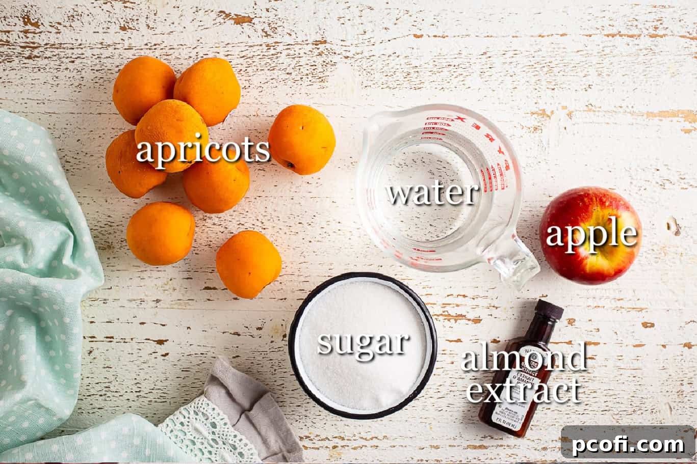 Various ingredients laid out for making apricot jam, including fresh apricots, an apple, sugar, and lemon.