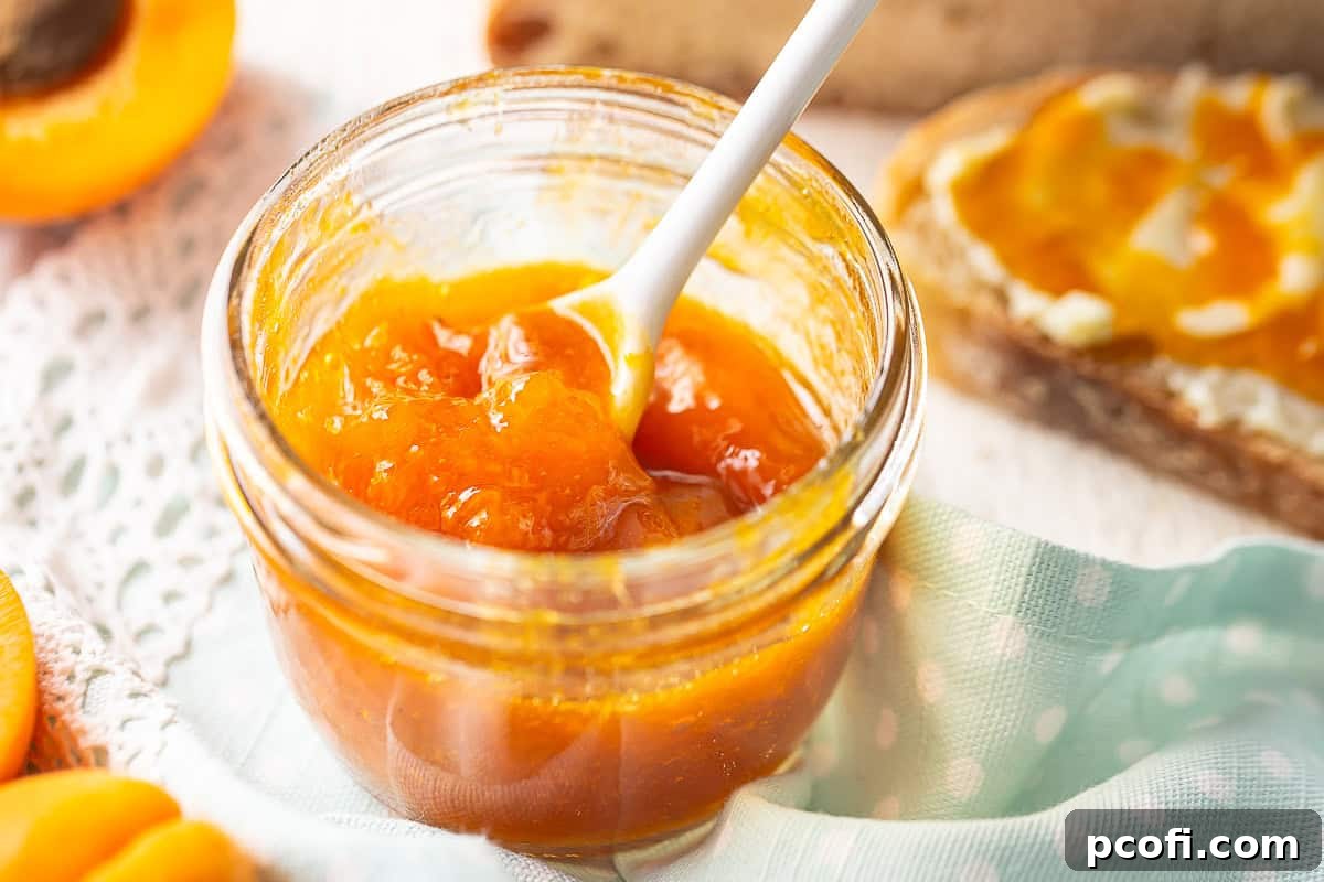 A jar of homemade apricot preserves with a slice of buttered toast in the soft background, inviting a delicious breakfast.